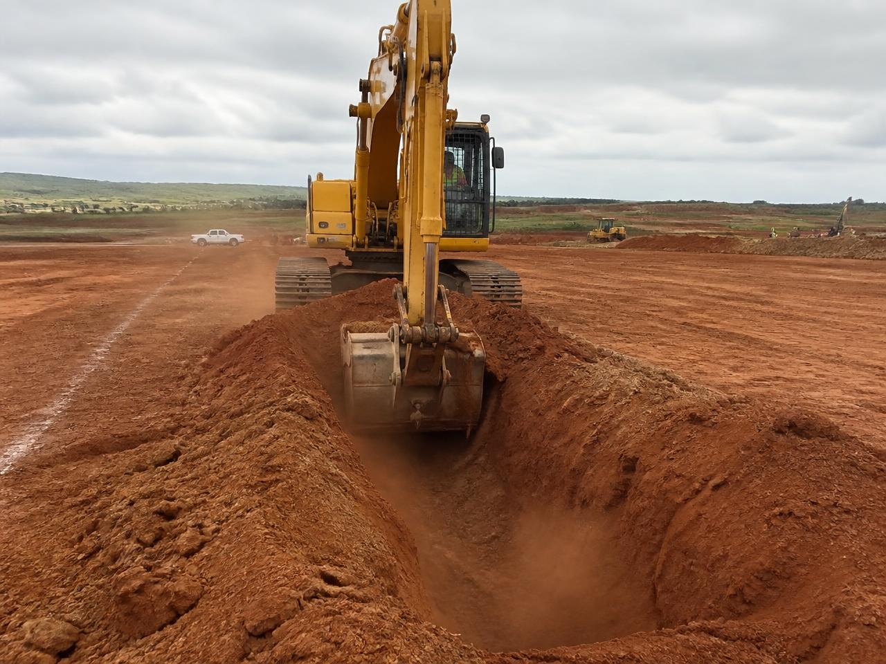 Close detail of an excavator arm and hydraulic rams working exposed ground